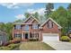 Attractive two-story brick home with manicured front lawn, mature trees, and a two-car garage at 1191 Crofton Lndg, Suwanee, GA 30024