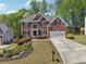 Charming red brick home with lush landscaping, a two-car garage, and a driveway at 1191 Crofton Lndg, Suwanee, GA 30024