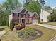 Charming red brick home with lush landscaping, a two-car garage, and a driveway at 1191 Crofton Lndg, Suwanee, GA 30024
