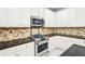 Close-up of stainless oven with granite countertops, backsplash, and stainless microwave at 1191 Crofton Lndg, Suwanee, GA 30024