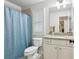 Bright bathroom with a granite countertop, window shutters, and blue shower curtain at 1870 Marcia Overlook Dr, Cumming, GA 30041