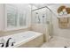Bathroom featuring a soaking tub with jets, a glass enclosed shower, and shuttered windows at 1870 Marcia Overlook Dr, Cumming, GA 30041