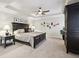 Bedroom features neutral carpeting, tray ceilings, a ceiling fan, and matching dark wood furniture at 1870 Marcia Overlook Dr, Cumming, GA 30041