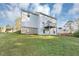 The home's rear with white siding, balcony, concrete basement wall, and sloping lawn at 7746 New Castle Way, Jonesboro, GA 30236