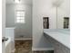 Bathroom showcasing a sink with vanity, tile floor, and window, with access to the tub area at 116 Shefield Pl, Douglasville, GA 30134
