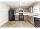 Kitchen featuring painted cabinets, black appliances, and worn vinyl flooring at 116 Shefield Pl, Douglasville, GA 30134