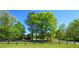 A large, well-manicured lawn with mature trees and a black fence lines the yard of this home at 20 Rivercreek Xing, Kingston, GA 30145