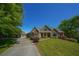 Stunning stone home with a well-manicured lawn, a long driveway, and mature trees on a sunny day at 20 Rivercreek Xing, Kingston, GA 30145