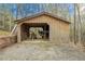 Wooden shed with open front, ideal for equipment or vehicle storage, nestled in wooded backyard at 5 Colonial Club Se Dr, Acworth, GA 30102