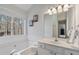 This bathroom with a large window, soaking tub, and white vanity is designed for relaxation and functionality at 3823 Briarstone Cv, Snellville, GA 30039