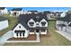 Aerial view featuring a white brick home with black accents and a manicured lawn in a suburban neighborhood at 7785 Wild Violet Dr, Cumming, GA 30040