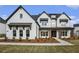 A stylish two-story home with white brick, black trim, covered entry and manicured front yard at 7785 Wild Violet Dr, Cumming, GA 30040