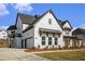 Side angle view of a two-story home featuring white brick, black trim, and a two-car garage at 7785 Wild Violet Dr, Cumming, GA 30040