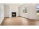 A modern living room features a fireplace, light wood floors, neutral paint, and large windows at 7785 Wild Violet Dr, Cumming, GA 30040