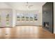 Bright living room with hardwood floors, fireplace, ceiling fan, and large windows at 7785 Wild Violet Dr, Cumming, GA 30040