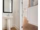 Elegant powder room with a pedestal sink, mirror, and stylish fixtures, located off the main hall at 7785 Wild Violet Dr, Cumming, GA 30040
