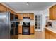 Well-lit kitchen featuring black appliances, wood cabinets, and a view into an adjacent room at 105 Ruff Harris Dr, Dallas, GA 30157