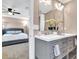 Bright bathroom featuring a gray vanity with double sinks and a glimpse of a bedroom with a gray tufted bed at 1094 Regent Sw St, Atlanta, GA 30310