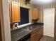 Galley-style kitchen with wood cabinets, granite countertops, stainless steel appliances, and laminate flooring at 6434 Wellington Chase Ct # 6434, Lithonia, GA 30058
