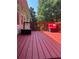 A well maintained, red-painted wooden deck with red cushions and views of the wooded backyard at 5915 Windsorcreek Dr, Douglasville, GA 30135