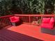 This red painted wood deck has ample seating and relaxing views of the trees at 5915 Windsorcreek Dr, Douglasville, GA 30135