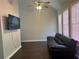 Living room with vaulted ceilings, hardwood floors, television, and a modern black leather couch at 5915 Windsorcreek Dr, Douglasville, GA 30135