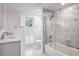 Bright bathroom with a marble vanity, tiled shower over tub with glass doors, and shuttered window at 2769 Peachtree Ne Rd # 10, Atlanta, GA 30305
