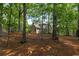 View of backyard with house nestled in a forest setting and spacious outdoor living area at 3895 Overlake Dr, Cumming, GA 30041