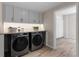 Well-lit laundry room featuring a front-load washer and dryer with overhead cabinets for ample storage at 3895 Overlake Dr, Cumming, GA 30041