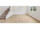 Spacious living room with wood-look flooring, a staircase, and a large window that allows lots of natural light at 28 Kensington St, Kingston, GA 30145