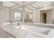 Elegant bathroom features a large soaking tub, marble tiling, and mirrors reflecting natural light at 906 John Ct, Lawrenceville, GA 30046