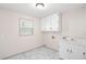 Bright laundry room featuring marble tile flooring, storage cabinets, a sink, and a window for natural light at 906 John Ct, Lawrenceville, GA 30046