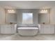 Luxurious bathroom featuring a modern soaking tub between two vanities beneath elegant lighting at 205 Haverling Pass, Hampton, GA 30228