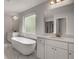 Elegant bathroom with a freestanding tub, dual vanities, mirrors, and modern lighting at 205 Haverling Pass, Hampton, GA 30228