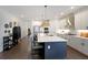 Bright, open kitchen featuring an island with bar seating, white cabinets, stainless steel appliances, and hardwood floors at 518 Newstead Way, Woodstock, GA 30188