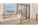 Bright bathroom featuring a soaking tub, tiled shower with glass doors, and a large window at 606 Discovery Ct, Acworth, GA 30102