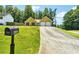 View of tan home with a two-car garage, surrounded by lush green lawn and mature trees at 6445 Marsham Dr, Atlanta, GA 30349