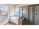 Bathroom with a tub and walk-in glass shower, complemented by neutral tiling and a bright window at 9942 Ashton Old Rd, Douglasville, GA 30135