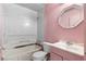 Dated pink bathroom featuring a shower-tub combo with marble surround, toilet, vanity, and an octagonal mirror at 126 Washington St, Mcdonough, GA 30253