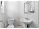 Modest bathroom with a pedestal sink, toilet, mirror, and a small window at 126 Washington St, Mcdonough, GA 30253