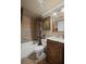 A well-lit bathroom features a vanity with carved wood accents, a shower with patterned curtains, and decorative art at 6597 River Island Dr, Buford, GA 30518
