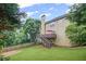 View of the back of the house with a deck, large yard, mature trees, and staircase, great for outdoor enjoyment at 6597 River Island Dr, Buford, GA 30518