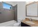 Well-lit bathroom featuring gray tiled walls, granite countertops, and tub with shower head at 482 Pearl Cove Ct, Atlanta, GA 30350