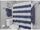 Bathroom showcasing a toilet, towel rack with blue towels, and a shower with a stylish blue and white striped curtain at 4162 Crowder Nw Dr, Kennesaw, GA 30152