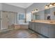 Bright bathroom with a glass-enclosed shower, soaking tub, and double vanity with gray cabinets and a large mirror at 4162 Crowder Nw Dr, Kennesaw, GA 30152