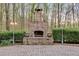 Stone outdoor fireplace with gas lamps surrounded by manicured bushes on a paved patio at 4231 Carrington Ct, Douglasville, GA 30135