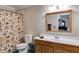 Bathroom with flowered shower curtain, toilet and oak vanity with white countertop and mirror at 4231 Carrington Ct, Douglasville, GA 30135