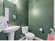 Stylish powder room with a pedestal sink, toilet, and painted green walls at 6407 Barker Station Walk, Sugar Hill, GA 30518