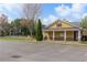 Charming yellow clubhouse with covered porch and manicured lawn near ample parking and community amenities at 6407 Barker Station Walk, Sugar Hill, GA 30518