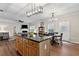 Open-concept kitchen island features wooden cabinets and granite countertops with dining area and adjacent living room at 6407 Barker Station Walk, Sugar Hill, GA 30518